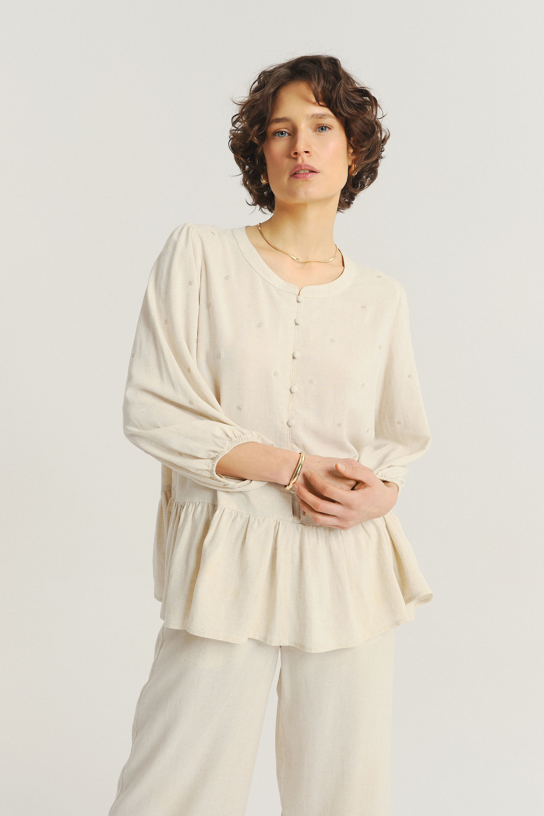 Jasnobeżowa bluzka z ozdobną falbanką u dołu