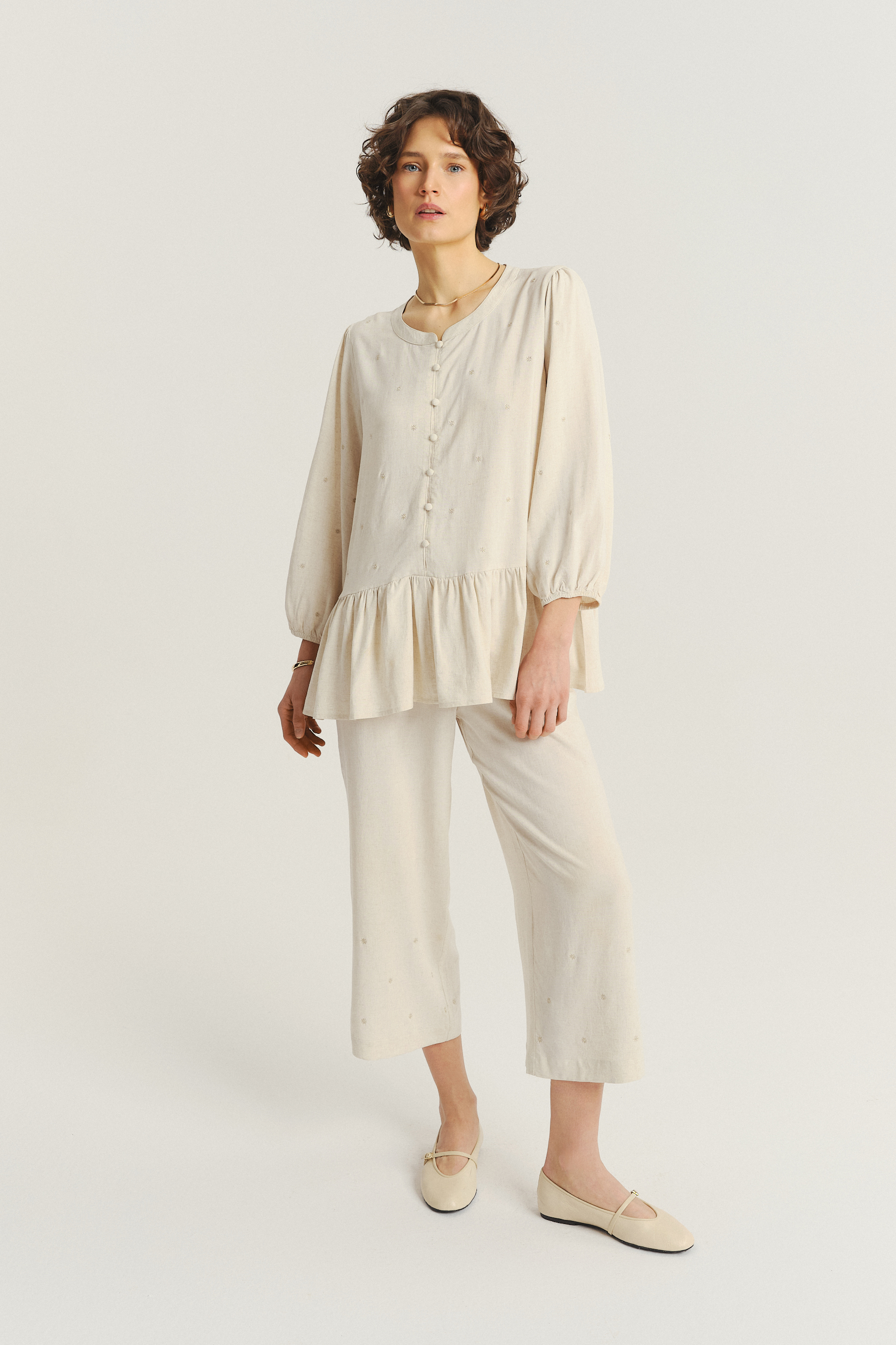 Jasnobeżowa bluzka z ozdobną falbanką u dołu