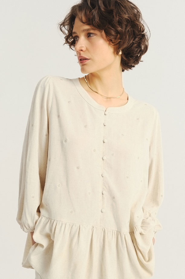 Jasnobeżowa bluzka z ozdobną falbanką u dołu