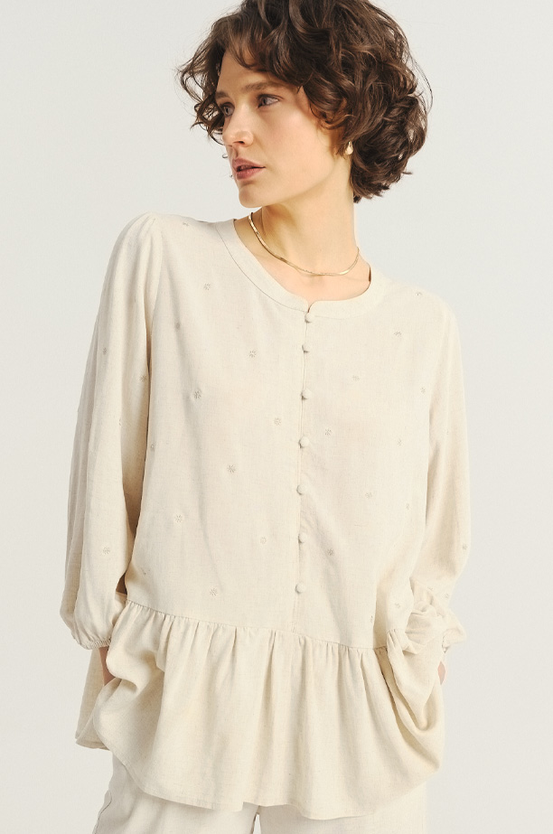 Jasnobeżowa bluzka z ozdobną falbanką u dołu