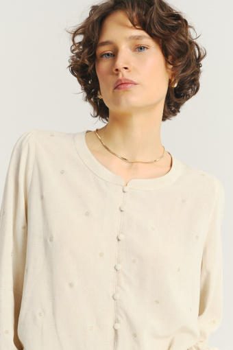 Jasnobeżowa bluzka z ozdobną falbanką u dołu