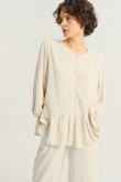 Jasnobeżowa bluzka z ozdobną falbanką u dołu
